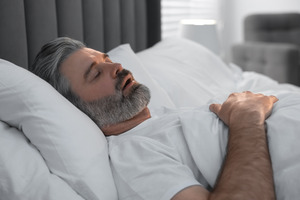 Bearded man lying in bed and snoring