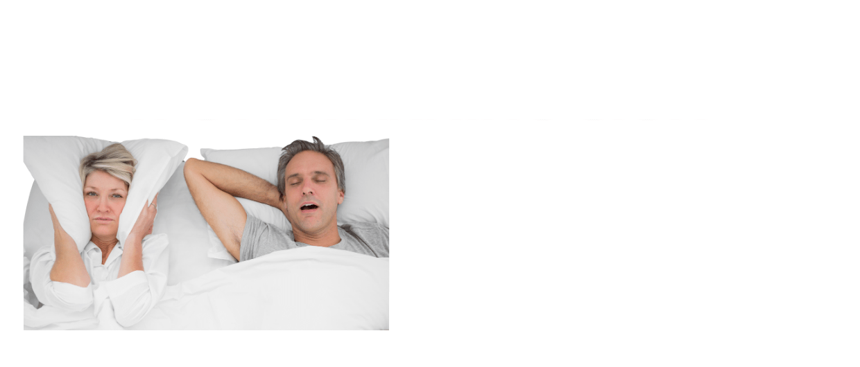 Woman covering her ears with a pillow next to a snoring man